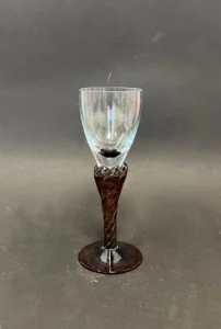 Szklany kieliszek z brązową, dekoracyjną nóżką.